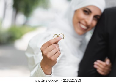 happy and blurred muslim bride holding wedding golden rings in hand
