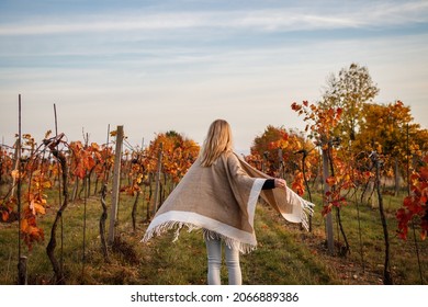 Happy boho woman with poncho running in autumn vineyard. Fall season in winery