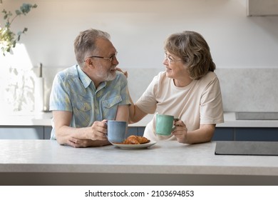 Happy bonding middle aged family couple enjoying pleasant conversation, drinking hot coffee or herbal green tea, talking speaking eating fresh croissants for tasty breakfast, family weekend concept. - Powered by Shutterstock