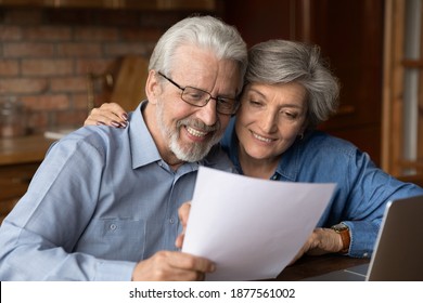 Happy Bonding Old Senior Family Couple Looking Through Paper Correspondence, Reading Letter With Good News. Curious Middle Aged Spouses Checking Bills Or Medical Insurance Contract Together At Home.