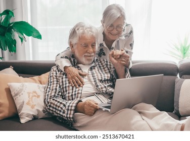 Happy bonding senior family couple stay together in living room using laptop. Grandparents enjoy surfing the internet, shopping online, watching something funny - Powered by Shutterstock