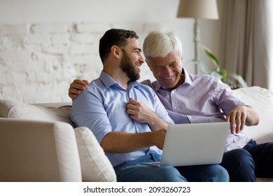 Happy bonding two male generations family looking at laptop screen, watching comedian film online or entertaining video in social network, laughing having fun together at home using modern tech gadget - Powered by Shutterstock