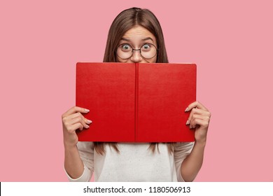 Happy Book Reader Hides Behind Textbook, Has Joyful Expression, Finds Out Something New, Has Interesting Hobby, Wears Round Big Spectacles For Good Vision. Female Geek Studies Informative Topic