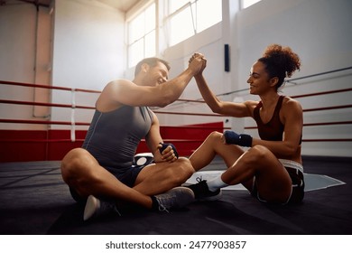 Happy boxing coach congratulating young sportswoman on successful training in health club. Copy space.