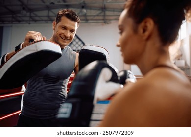 Happy boxing coach and female fighter having sports training in health club. - Powered by Shutterstock