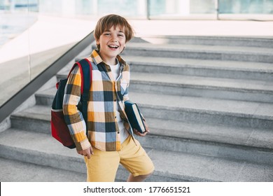 Happy boy with a backpack and a book goes to school. Beginning of the new school year after the summer holidays.