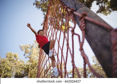 Happy boy cheering while climbing a net during obstacle course in boot camp - Powered by Shutterstock