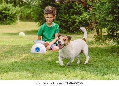 Happy boy and dog playing with automatic trow and fetch machine launching tennis balls