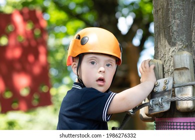 A Happy Boy With Down Syndrome In An Orange Helmet Goes Through A Difficult Sports Task, A Disabled Child, Children's Sports Entertainment.