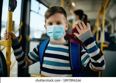 Happy Boy With Face Mask Commuting To School By Bus And Waving To Camera. 