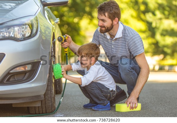 The happy boy and a\
father washing a car