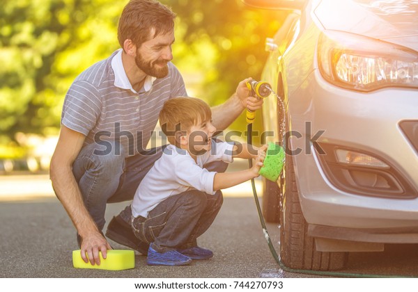 The happy\
boy and the father washing a car\
outdoor