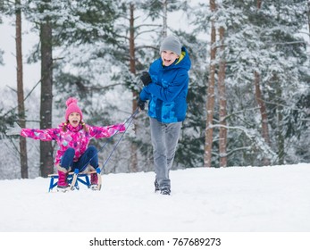 happy boy and girl riding sled and having fun children play outdoors in snow - Christmas Vacation Sled happy boy and girl riding sled and having fun children play outdoors in snow - Christmas Vacation Sled