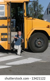 Happy Boy With Glasses Getting Off The Yellow School Bus After The First Day Of School.