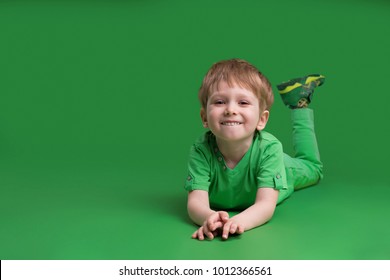 Happy Boy In Green Clothes Posing At Camera Against Green Background 