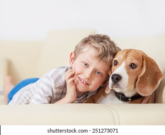 Happy boy with his dog lying on sofa