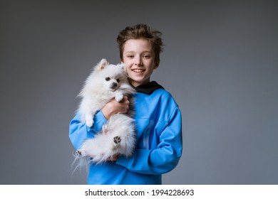 Happy Boy Holding Dog On Gray Background