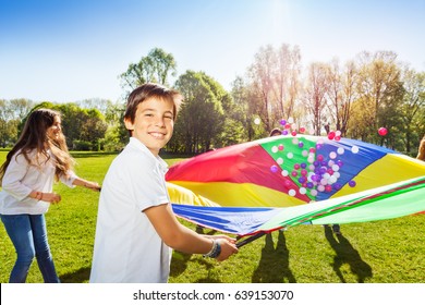 Happy boy holding parachute full of colorful balls