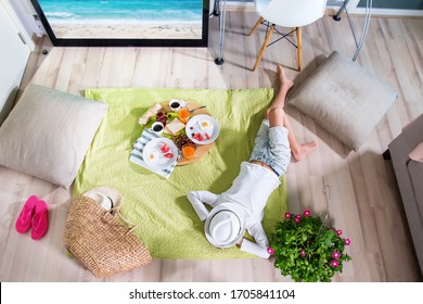 Happy boy are imitating picnic lying on grass on an open air on green grass at home near TV screen. Have fun with family. Coronavirus situation in tourism industry. Quarantine. Isolation from covid19
