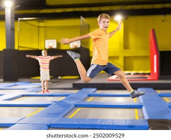 Happy boy jumping on trampoline park in sport center