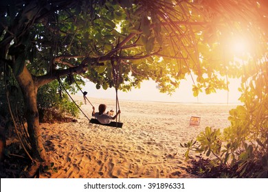 Happy Boy Kid On Swing Enjoy Freedom And Summer On Sea Shore On Sunset