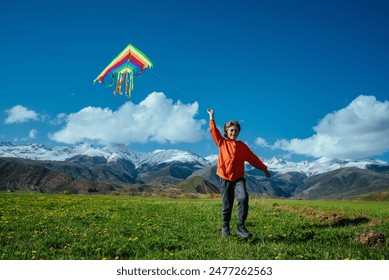 Happy boy with kite on green field on mountains background - Powered by Shutterstock