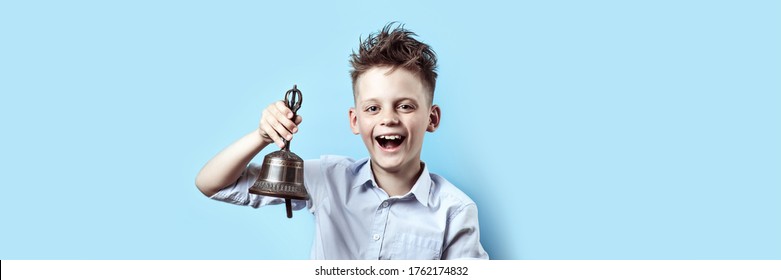 Happy Boy In Light Shirt Goes To School. He Has A Bell In His Hand, Which He Rings And Smiles.