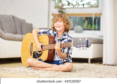 Happy Boy Making Music Playing The Guitar At Home