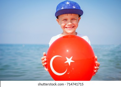 Happy Boy On Sea, Turkey. Smilling Child With Ballon Of Turkish Flag. Holiday On Sea Beach.