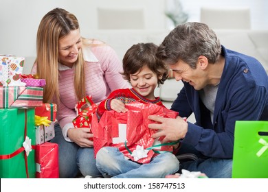 Happy Boy And Parents Opening Christmas Present At Home