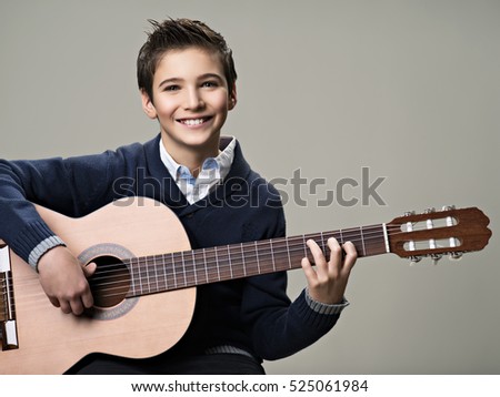 Happy boy playing on acoustic guitar. Teenager boy with classic wooden guitar