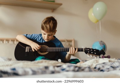 Happy boy playing on the guitar in his room. - Powered by Shutterstock
