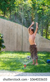 Happy boy playing with water sprinkler