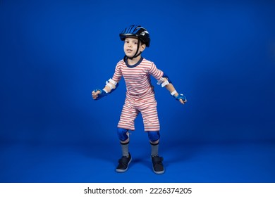 A happy boy in a protective helmet, elbow pads and gloves on a blue background. Protection when riding a bicycle, skateboard, roller skate - Powered by Shutterstock