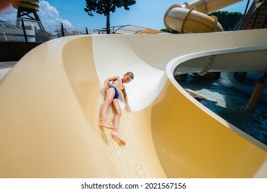 A happy boy of seven years old descends from the slides in the water park. Happy vacation vacation. Summer holidays and tourism. - Shutterstock ID 2021567156