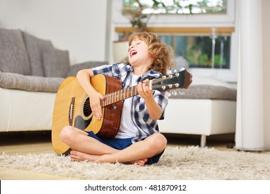Happy Junge zu Hause singen und Gitarre spielen
