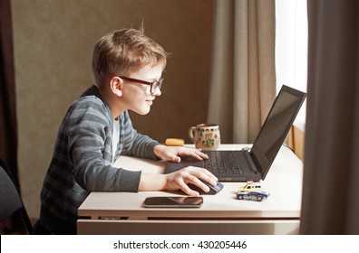 Happy boy sitting at his desk With laptop computer