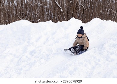 happy boy slides down an ice slide in winter outside - Powered by Shutterstock