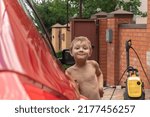 happy boy smiling and grimacing while standing next to the car
