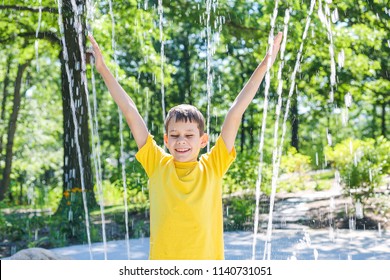 happy boy splashing in a fountain. laughing child enjoys the water playground