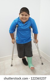 Happy boy standing with crutch in clinic