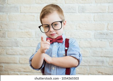 Happy boy standing with a finger in big glasses. The concept of the good boss - Shutterstock ID 1054365503