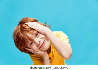 Happy boy touches his face with his hands and bent over to the side