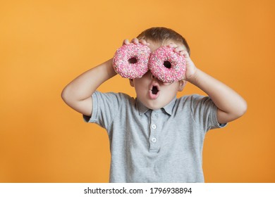 Happy boy with two donats on orange background - Shutterstock ID 1796938894