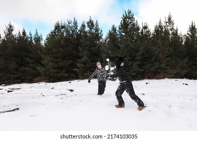 Happy Boys Playing In Snowy Winter Wonderland Having Snowball Fight