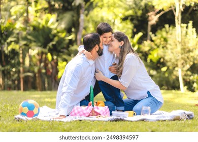 Happy brazilian  family enjoying a picnic in a sunny park. Parents embrace their child, creating a warm and affectionate scene. A moment filled with love, laughter, and togetherness. - Powered by Shutterstock