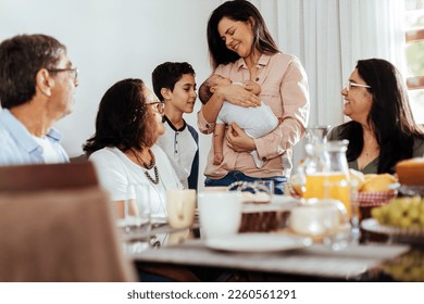 Happy Brazilian multi-generation family having breakfast together and talking at the table. Extended family meeting the newborn. - Powered by Shutterstock