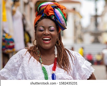 Happy Brazilian woman of African descent dressed in traditional Baiana costumes in the Historic Center of Salvador da Bahia, Brazil.
