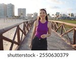 Happy Brazilian young woman walking on pier at sunset on Aracaju beach, Sergipe, Brazil