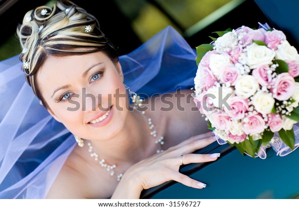 happy bride\
with flower bouquet siting in the\
car